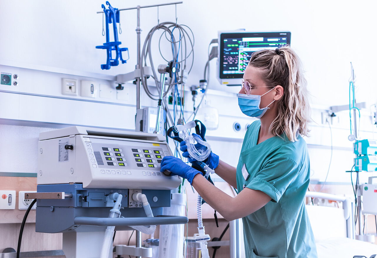 Hochreiner steriler Sauerstoff vor Ort Krankenschwester mit OP-Maske trägt, überprüft die Einstellungen eines mechanischen Beatmungsgeräts mit reinem Sauestoff